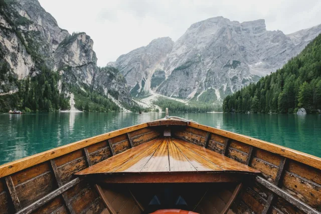 A wooden boat on a lake surrounded by forest and mountains