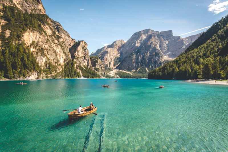 Rowboats on a turquoise lake beneath forested mountain slopes